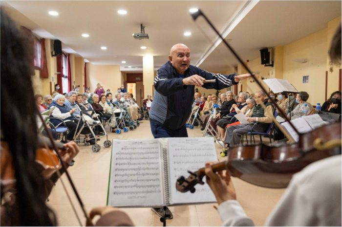 Persona mayor dirigiendo una orquesta.