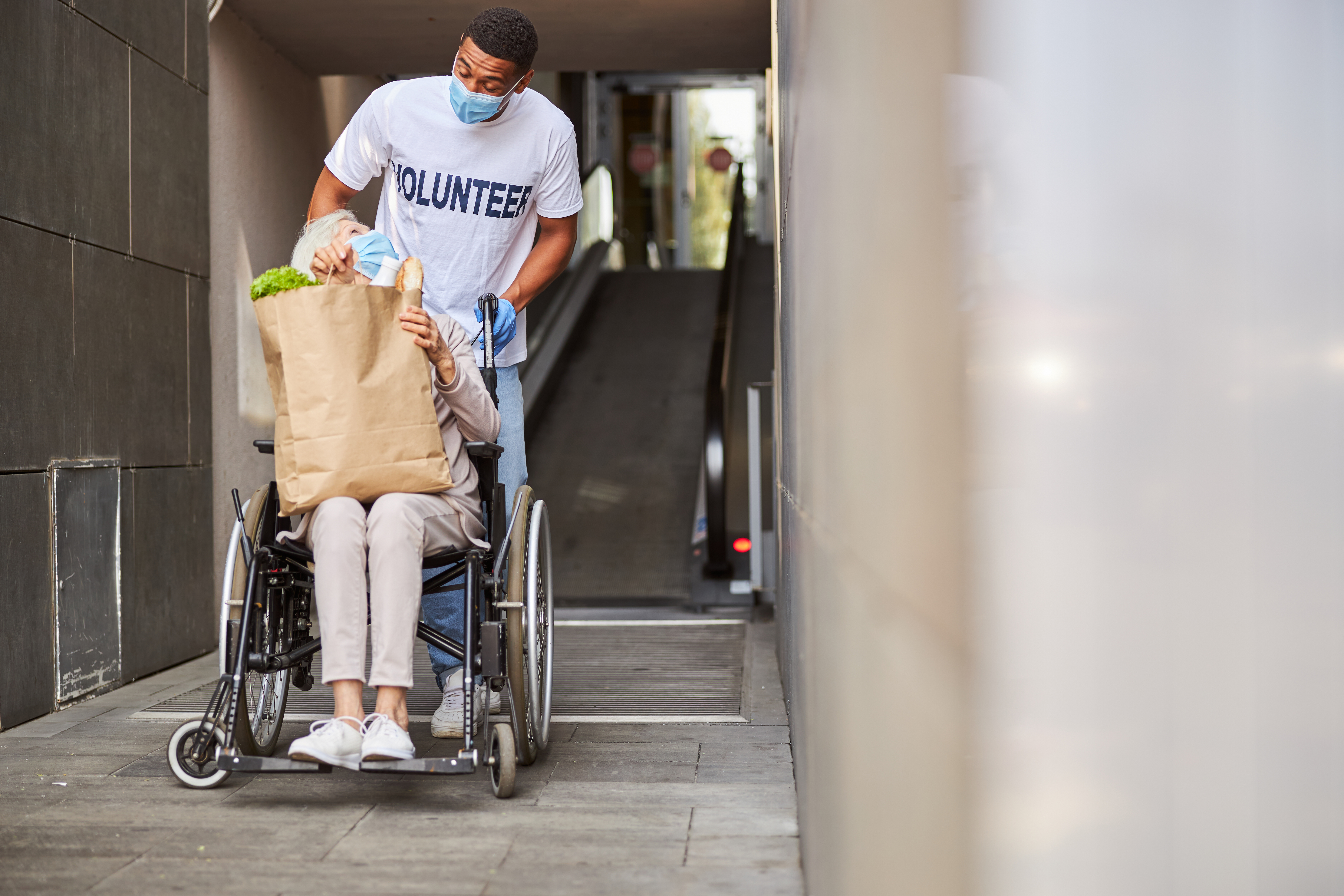 Voluntario ayudando a una persona mayor en silla de ruedas