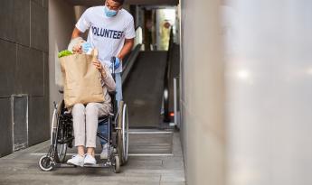 Voluntario ayudando a una persona mayor en silla de ruedas