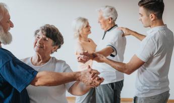 Personas mayores bailando en pareja en una clase llevada por una persona joven